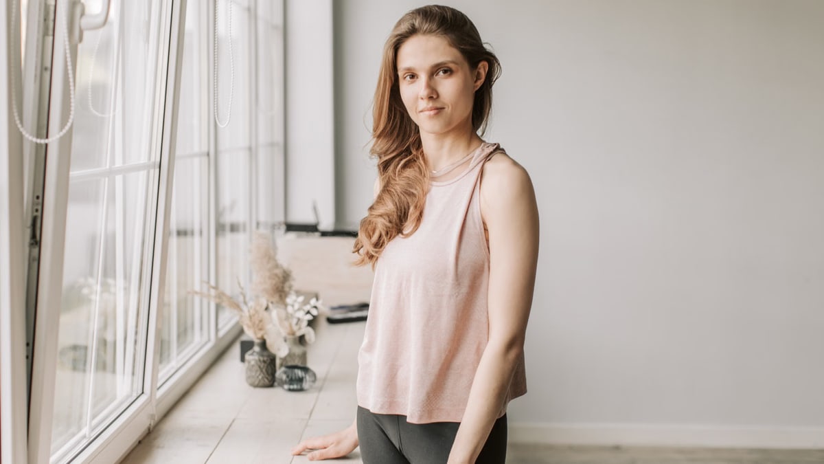 A young woman stands next to a sunlit windowsill, creating a tranquil ambiance.